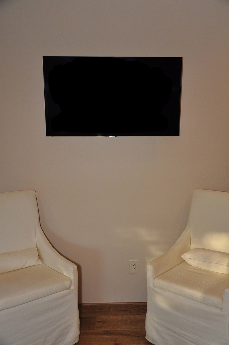 Guest room TV, mounted on the wall, with hidden components behind it, including a wireless access point